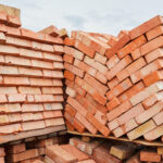 A stack of red clay bricks in rows close up. Lot of stacks of br
